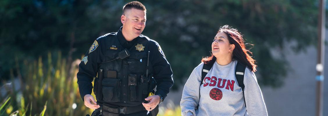 A male officer and female student walking on campus.