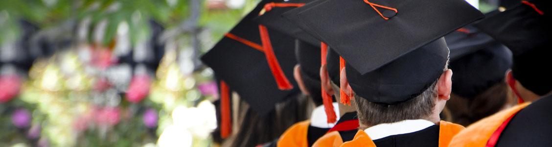 Students at graduation wearing their caps, seen from behind.