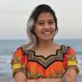 Lucia Ixchiu standing with arms crossed in colorful shirt in front of the ocean