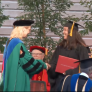 Student shaking hands with C S U N president at graduation