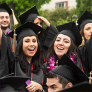 Two female CSUN students with hands in the air celebrating their graduation.