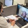 A female student is shown videoconferencing with another female student in class.
