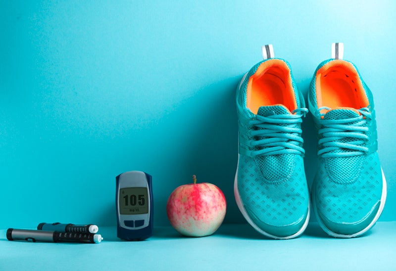 Apple, jumprope, and shoes against a wall