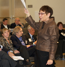 CSUN President Koester holding Volunteer Leadership Summit program in frond of audience.